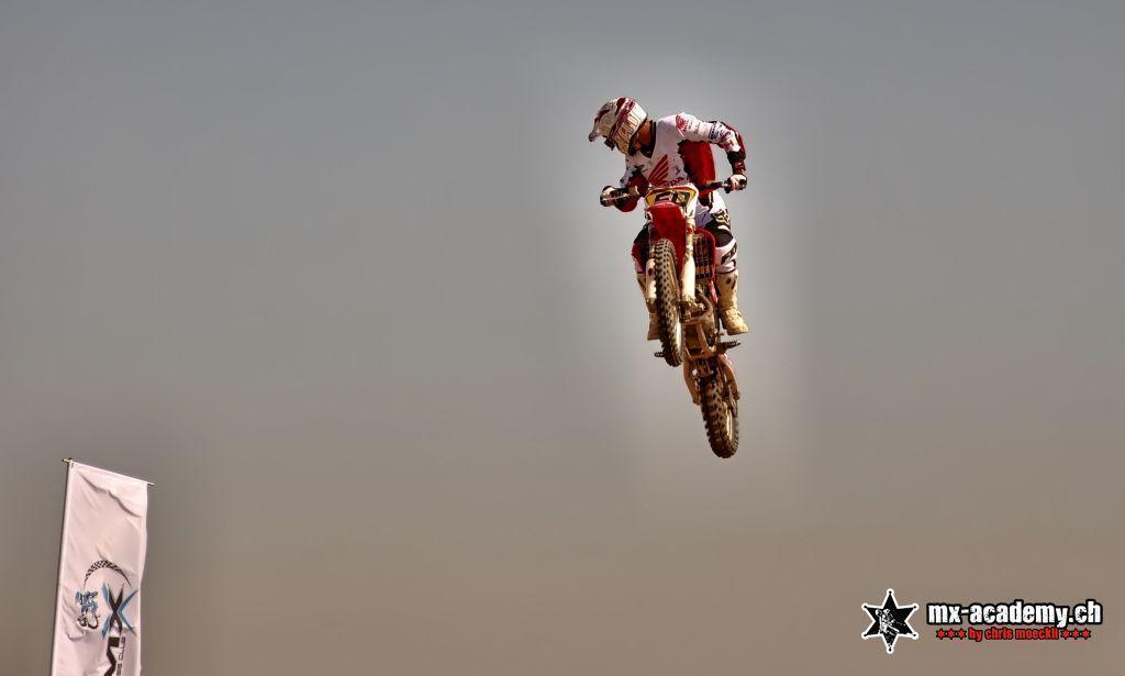 Motocross-Fahrer springt hoch über den Wüstensand bei Dubai