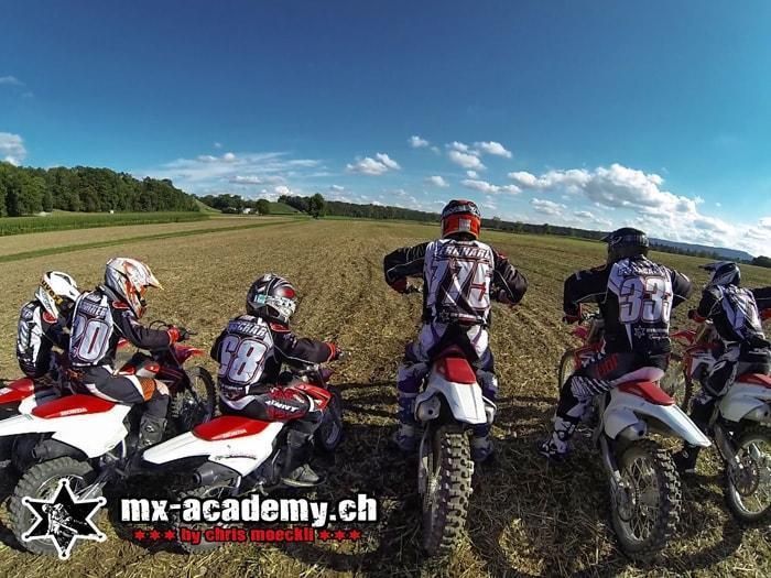 Fahrergruppe des Motocross Teams mit Honda Bikes vor dem Start auf dem Feld