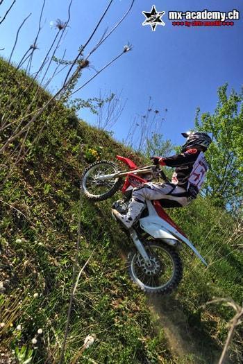 Fahrer erklimmt mit dem MX-Bike einen steilen, bewachsenen Hang