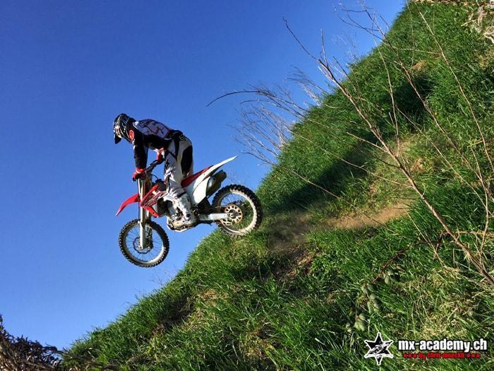 Trial-Übung am steilen Grashang mit einem roten Honda Motocross Bike
